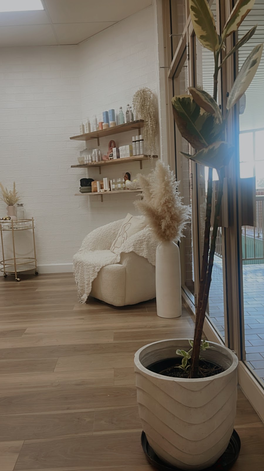 The bright lounge at Pure Soul, with a white armchair, pampas grass and shelves of skincare
