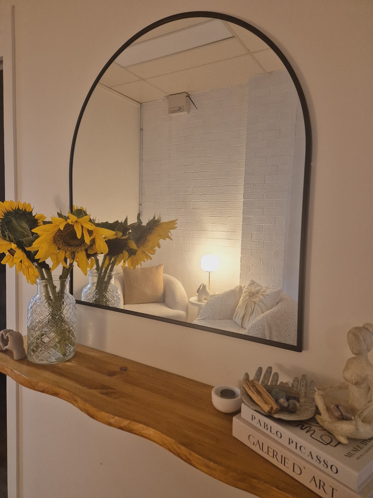 Arched mirror above a timber shelf with sunflowers