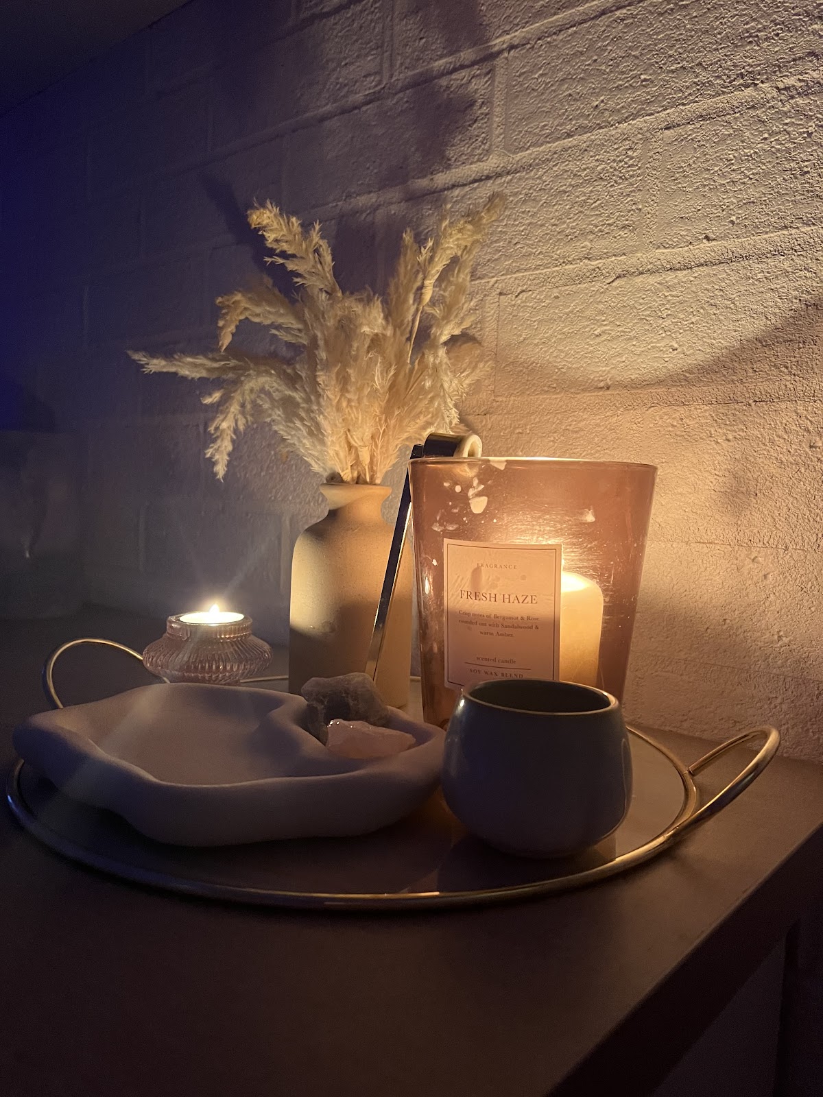 Candles and pampas on a tray against dark brick